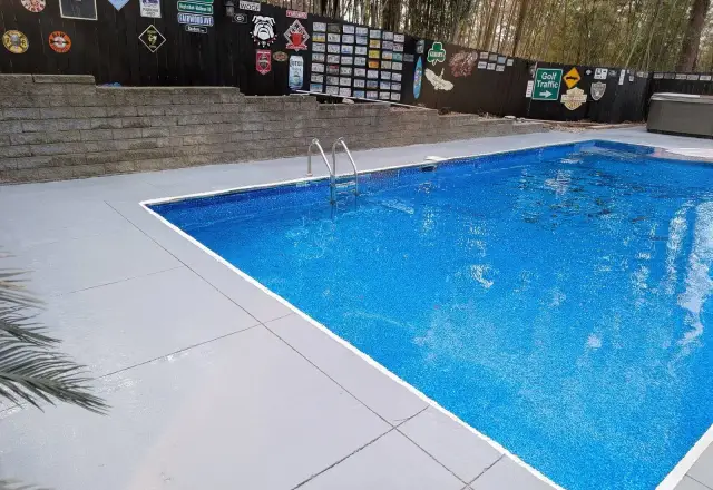 Coated pool deck around a bright blue in-ground pool