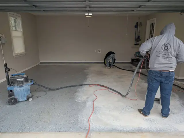 Crew diamond-grinding a garage slab before coating