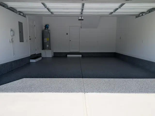 Garage with a dark flake floor and black stem wall