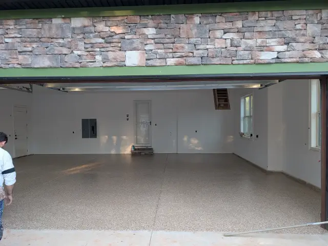 Three-car garage under a stone facade, light flake floor