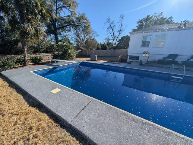 Textured gray pool surround beside a blue pool