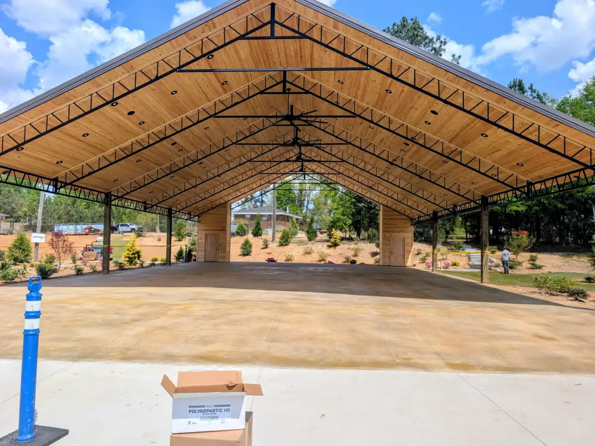 Warm-toned stained concrete floor beneath an open timber pavilion